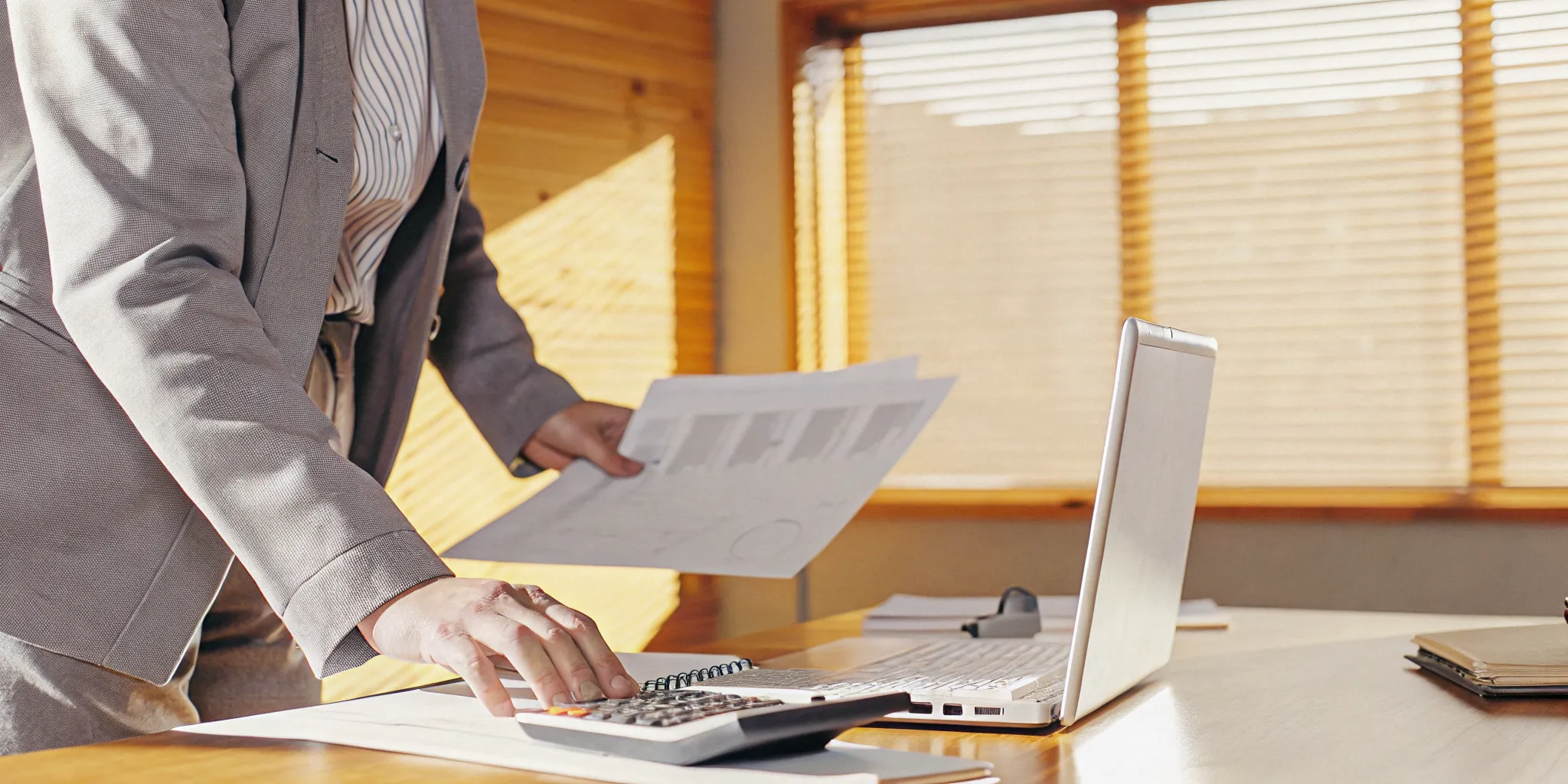Small business owner reviewing financial documents on a desk with laptop and calculator