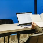 Small business owner reviewing paperwork at desk with laptop in modern office